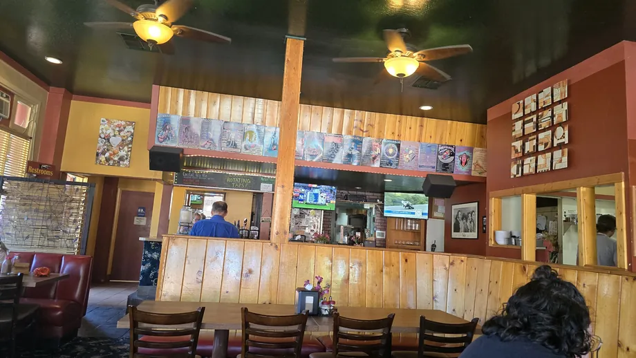 Knotty-pine dining room and wooden bar counter with beer tap signage, ceiling fans and red chairs